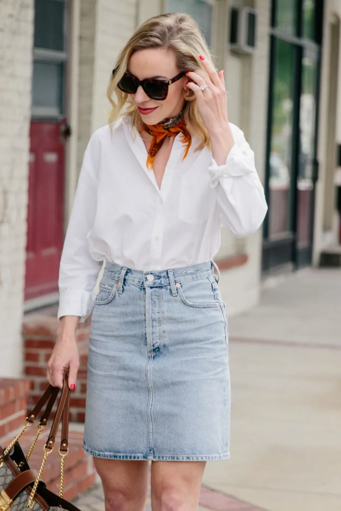 Meagan Brandon fashion blogger of Meagans Moda styles a white button down shirt for summer with neck scarf and light blue denim skirt